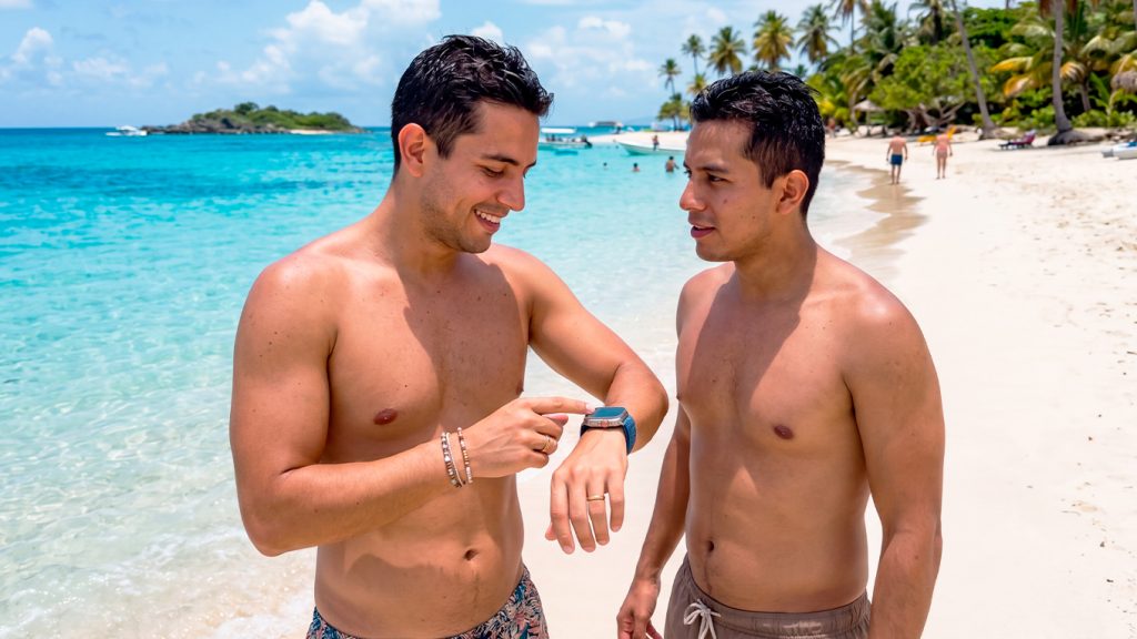 Dos viajeros en la playa revisando la hora como parte de sus cábalas del viajero