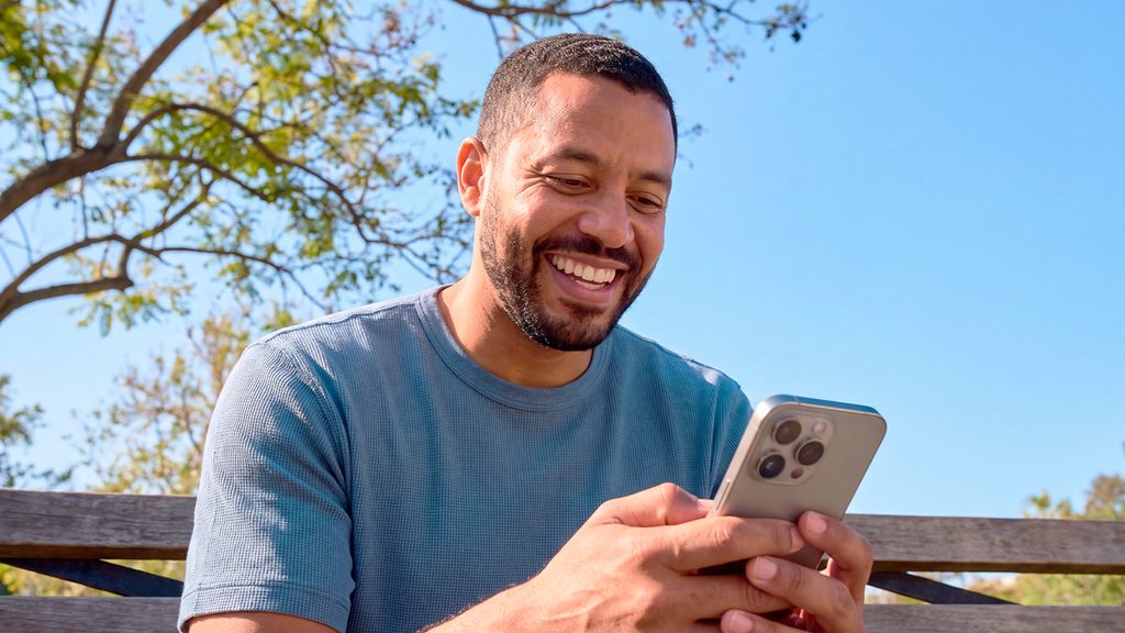 Hombre sonriente usando el celular para decidir qué lotería elegir