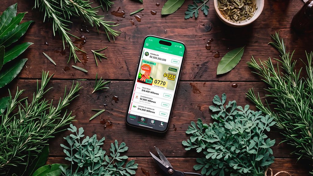 Celular con la app de TuLotero entre hierbas asociadas a los agüeros para la suerte.